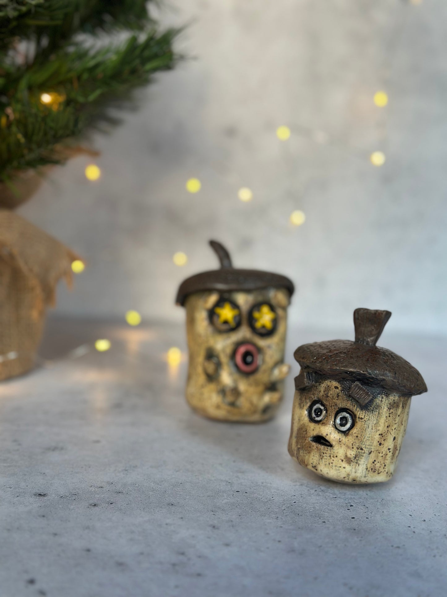 Two acorns with face designs on a light background with blurred lights.