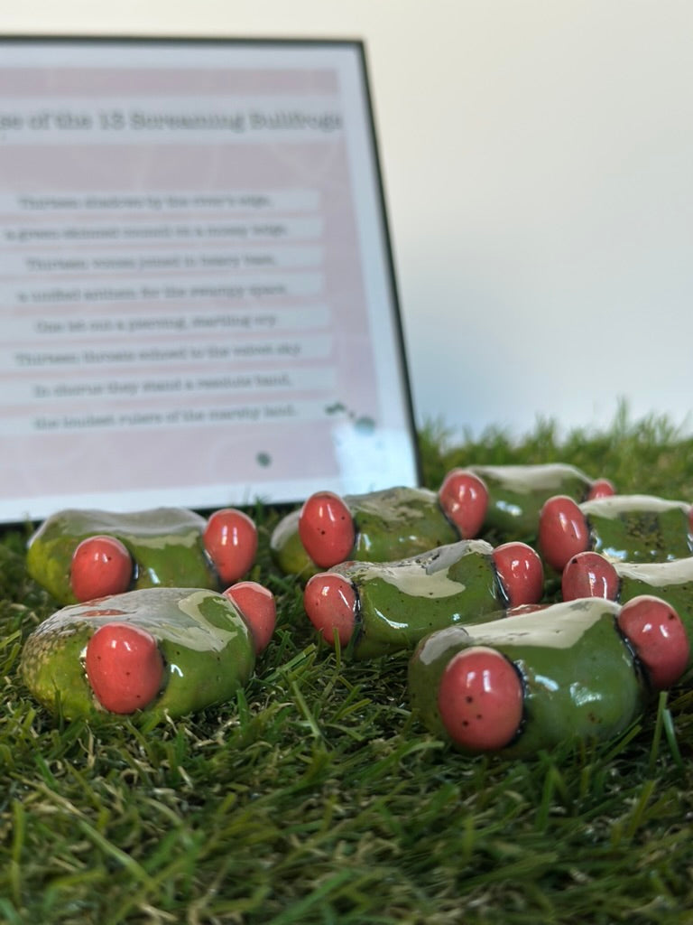 Ceramic frogs on grass with a blurred document in the background