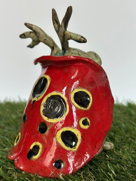 Ceramic ladybug figurine on grass with a white background