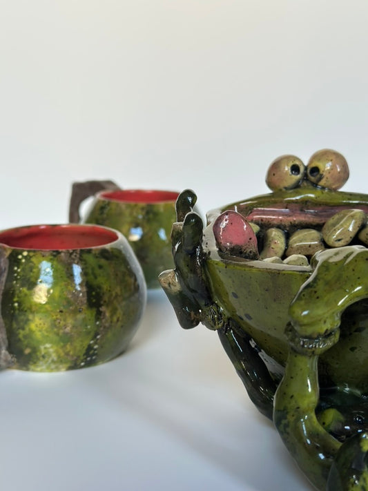 Ceramic lizard figurine blending with watermelon mugs