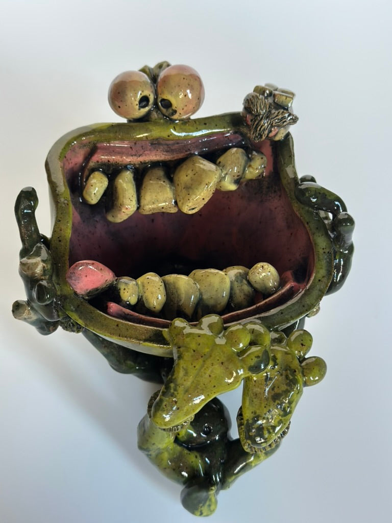 Ceramic sculpture of a mouth with teeth and eyes on a white background