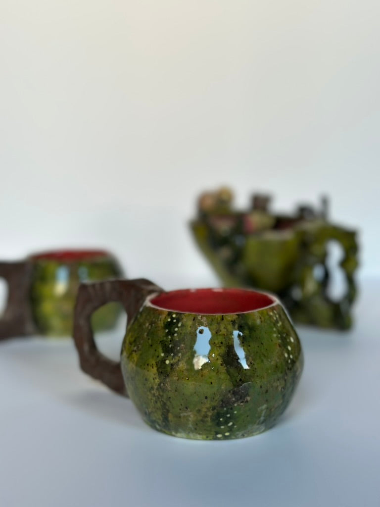 Green ceramic cups with red interior on a white background
