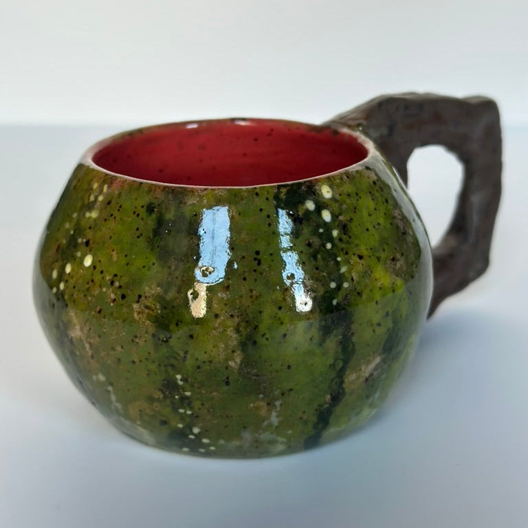 Green ceramic mug with a red interior on a white background