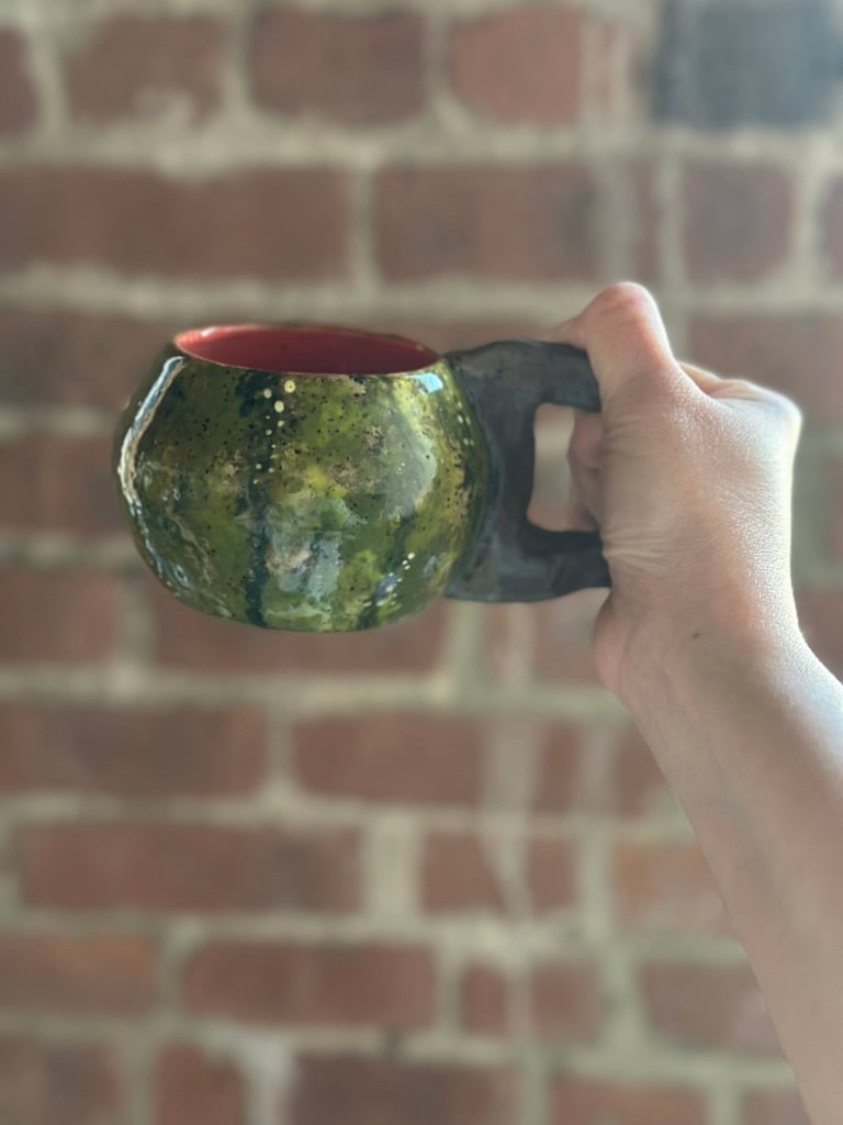 Hand holding a ceramic watermelon mug