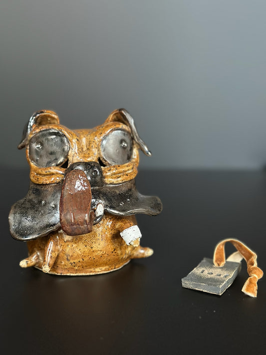 Ceramic dog (pug) sculpture a small rectangular tag on a dark surface