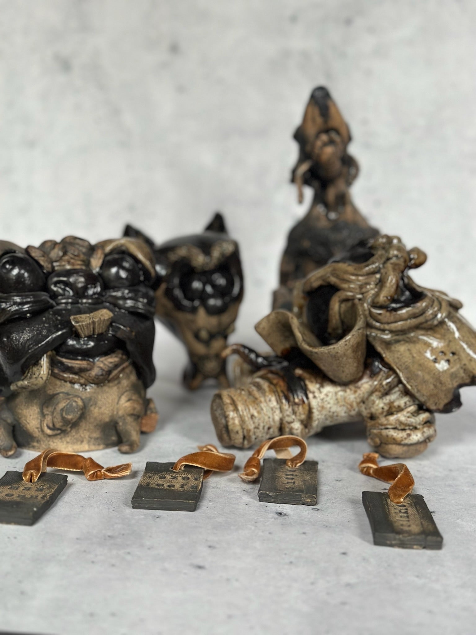 Ceramic dog sculptures with name tags on a gray surface