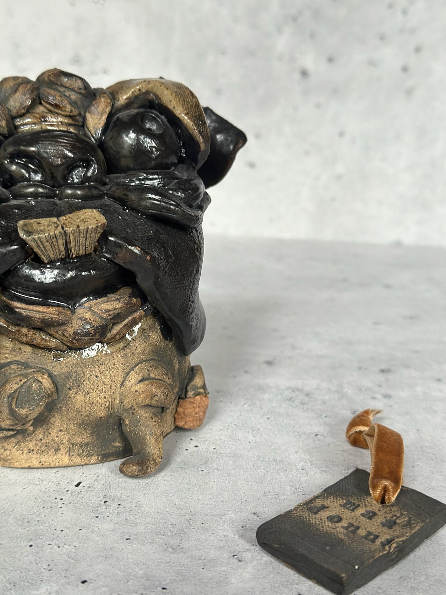 Decorative statue of a pug with a small tag on a gray surface