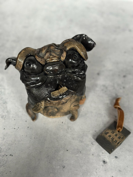 Ceramic sculpture of a pug dog on a concrete surface
