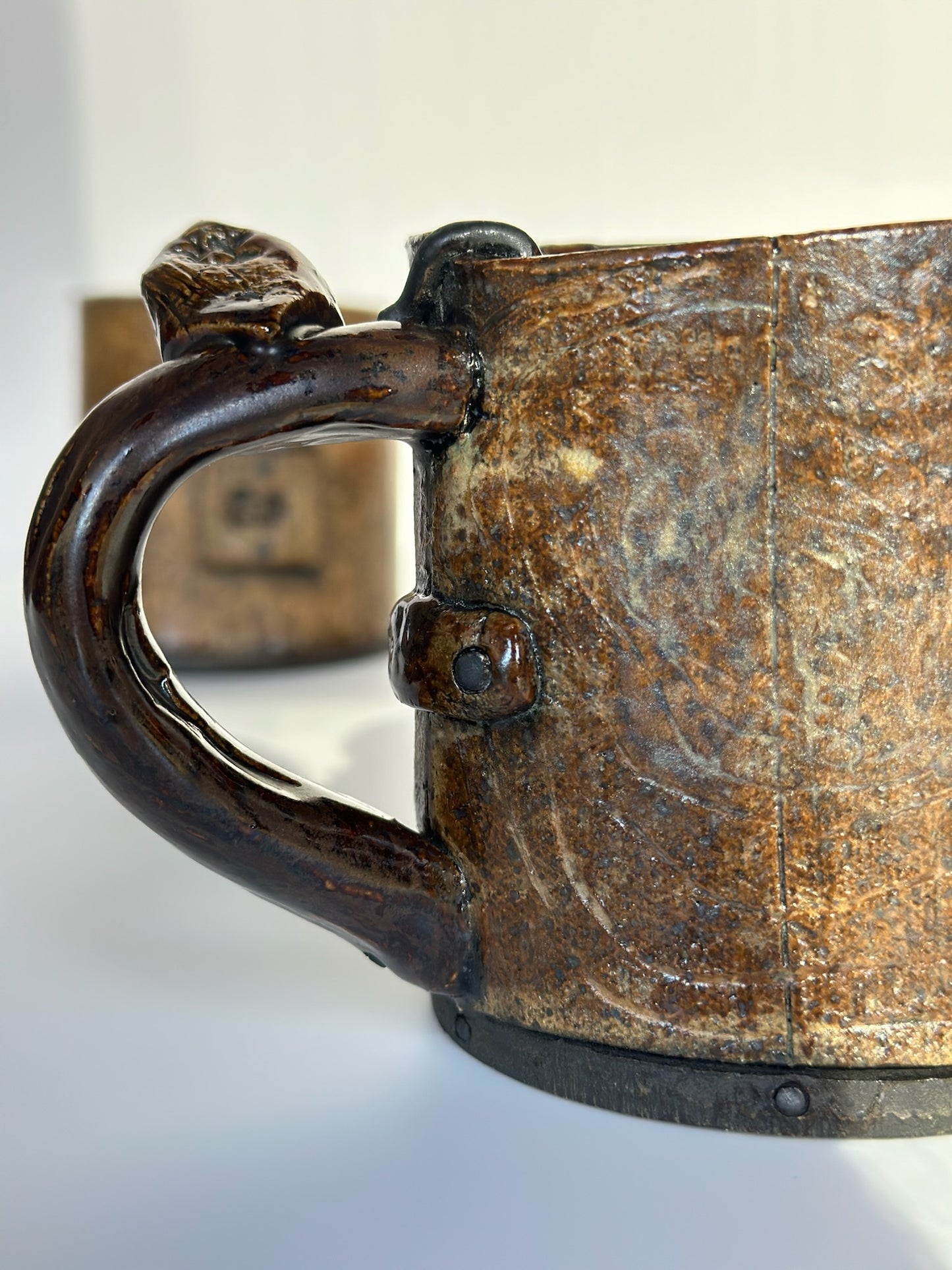 Close-up of a rustic metal mug with a handle on a white background