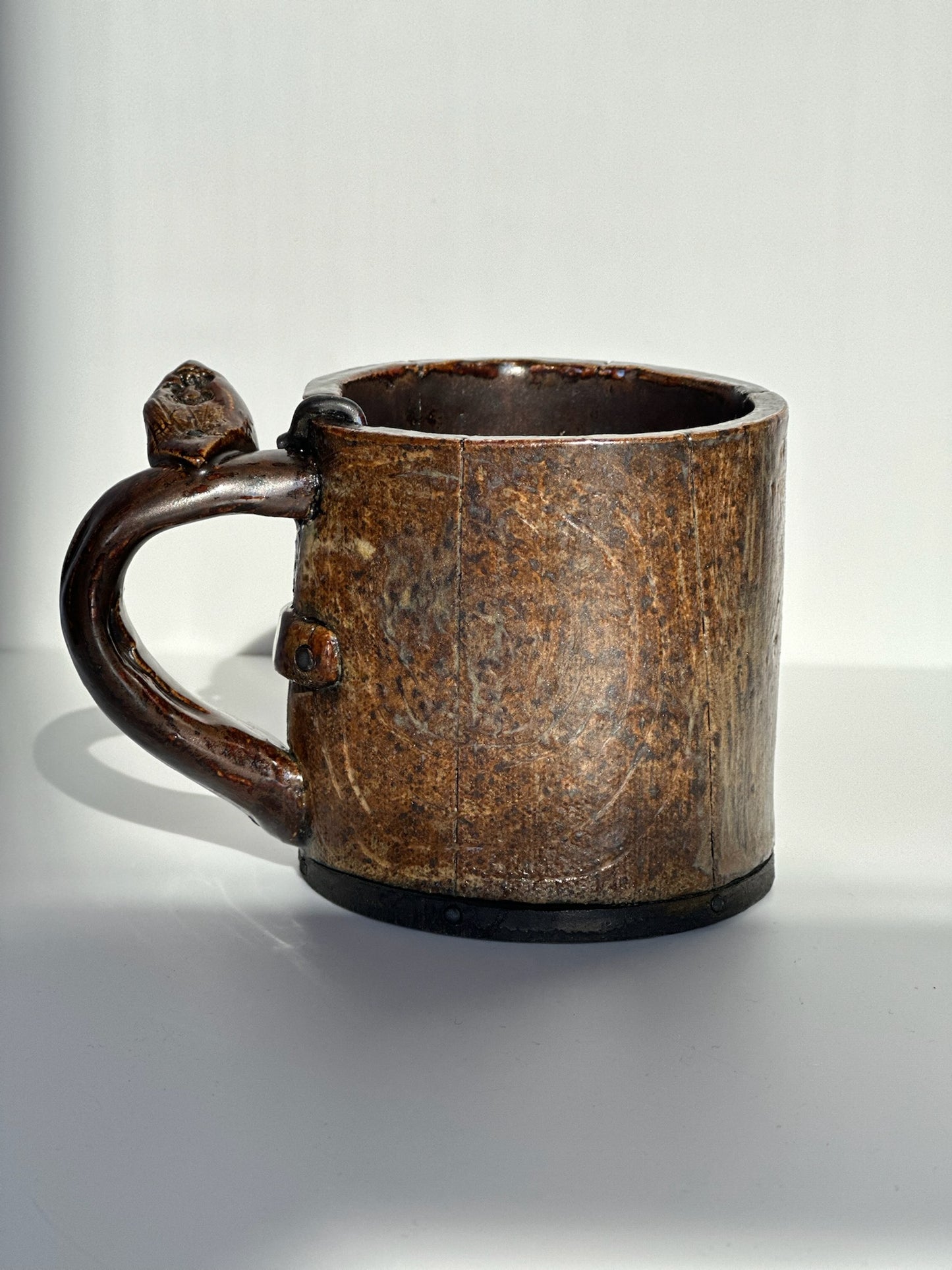 Brown ceramic mug with a handle on a white background