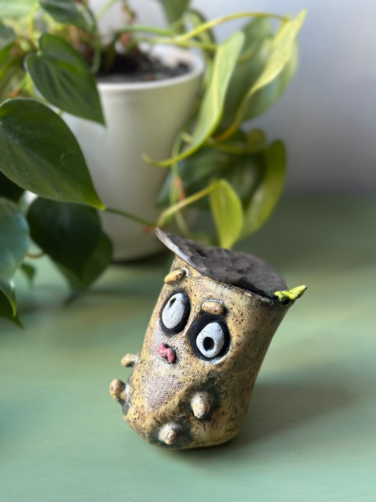 Ceramic acorn figurine with a plant in the background