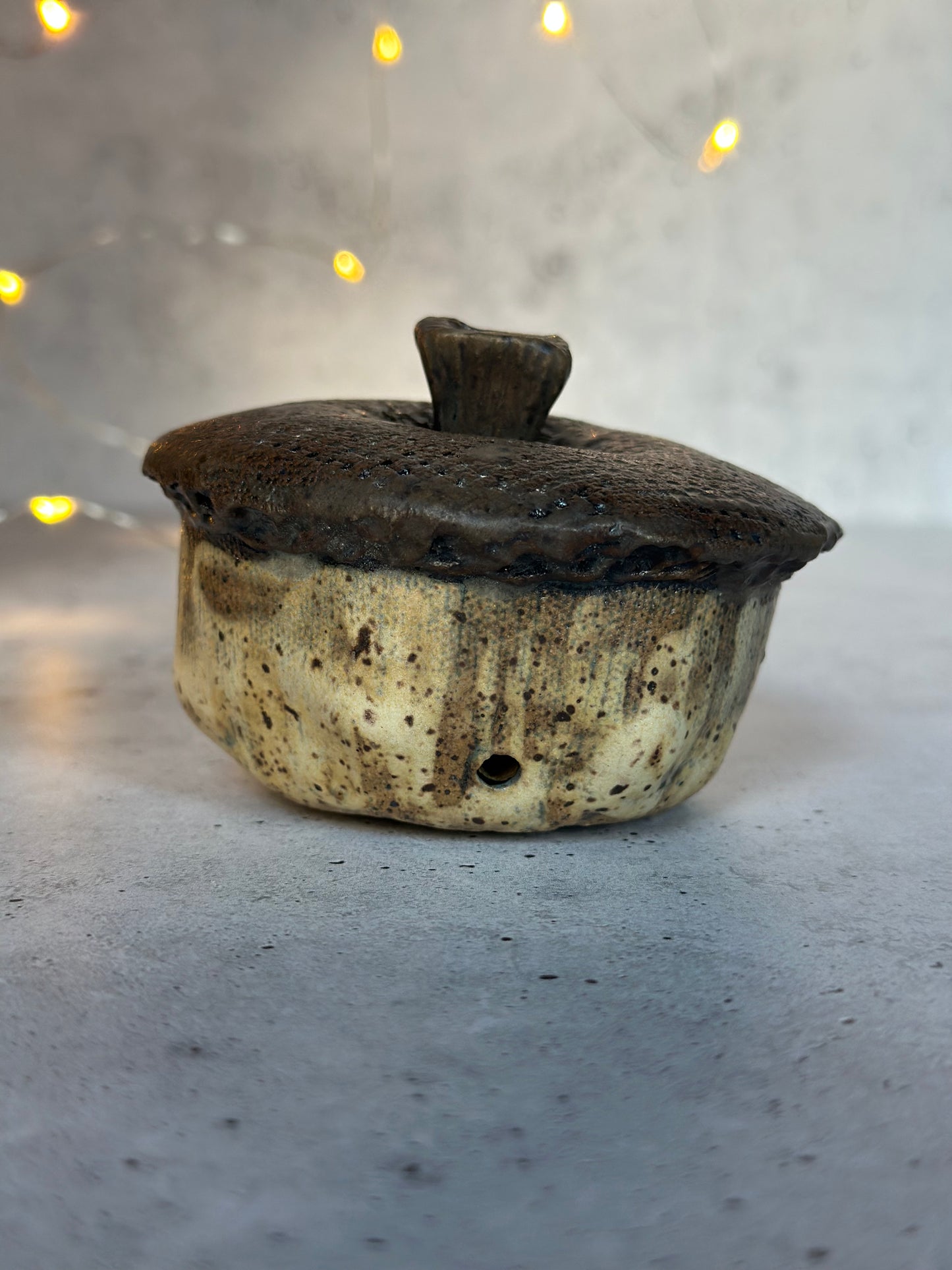 Ceramic acorn on a gray surface with blurred lights in the background