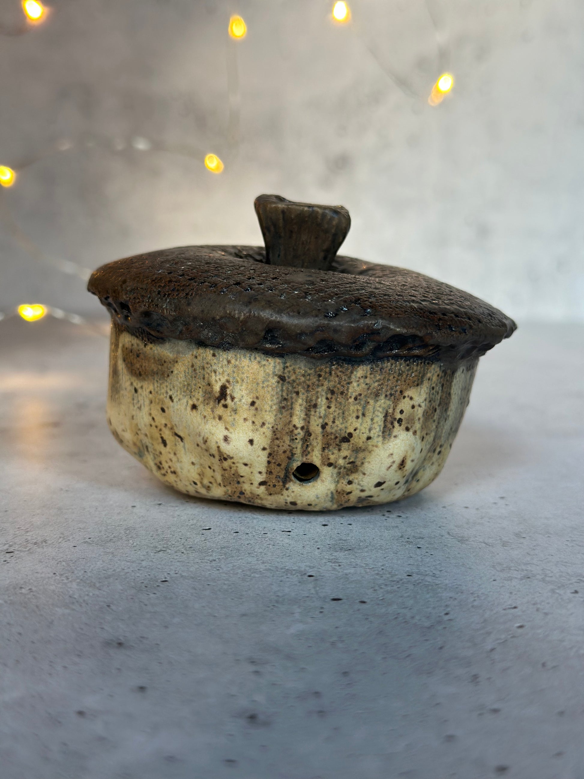 Ceramic acorn on a gray surface with blurred lights in the background