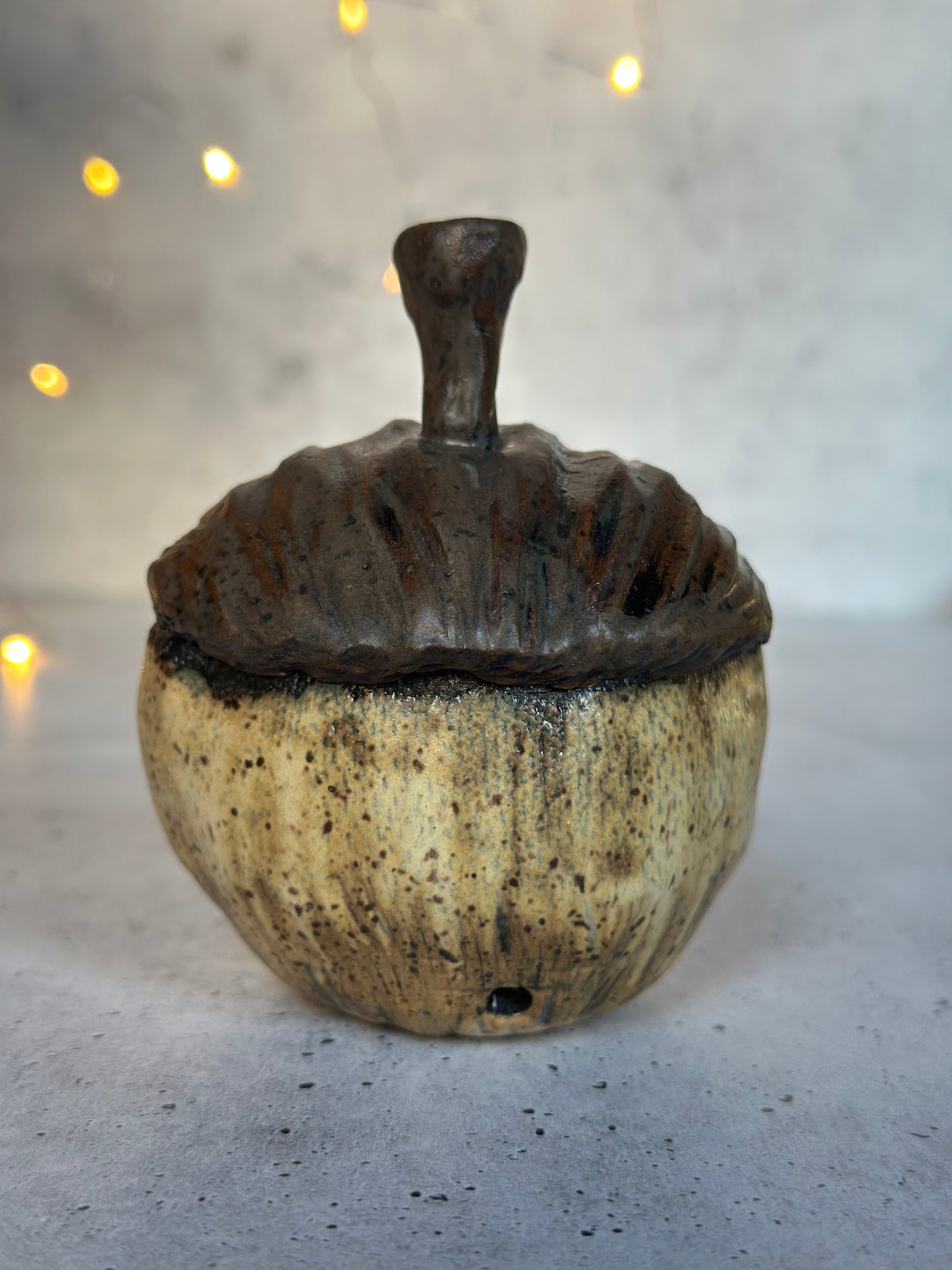 Decorative ceramic acorn with a textured surface on a neutral background
