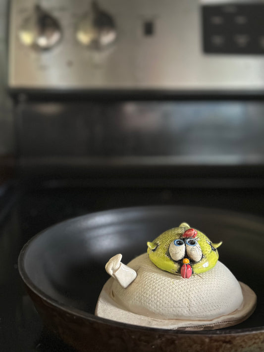 Ceramic chick on a pan on the stove