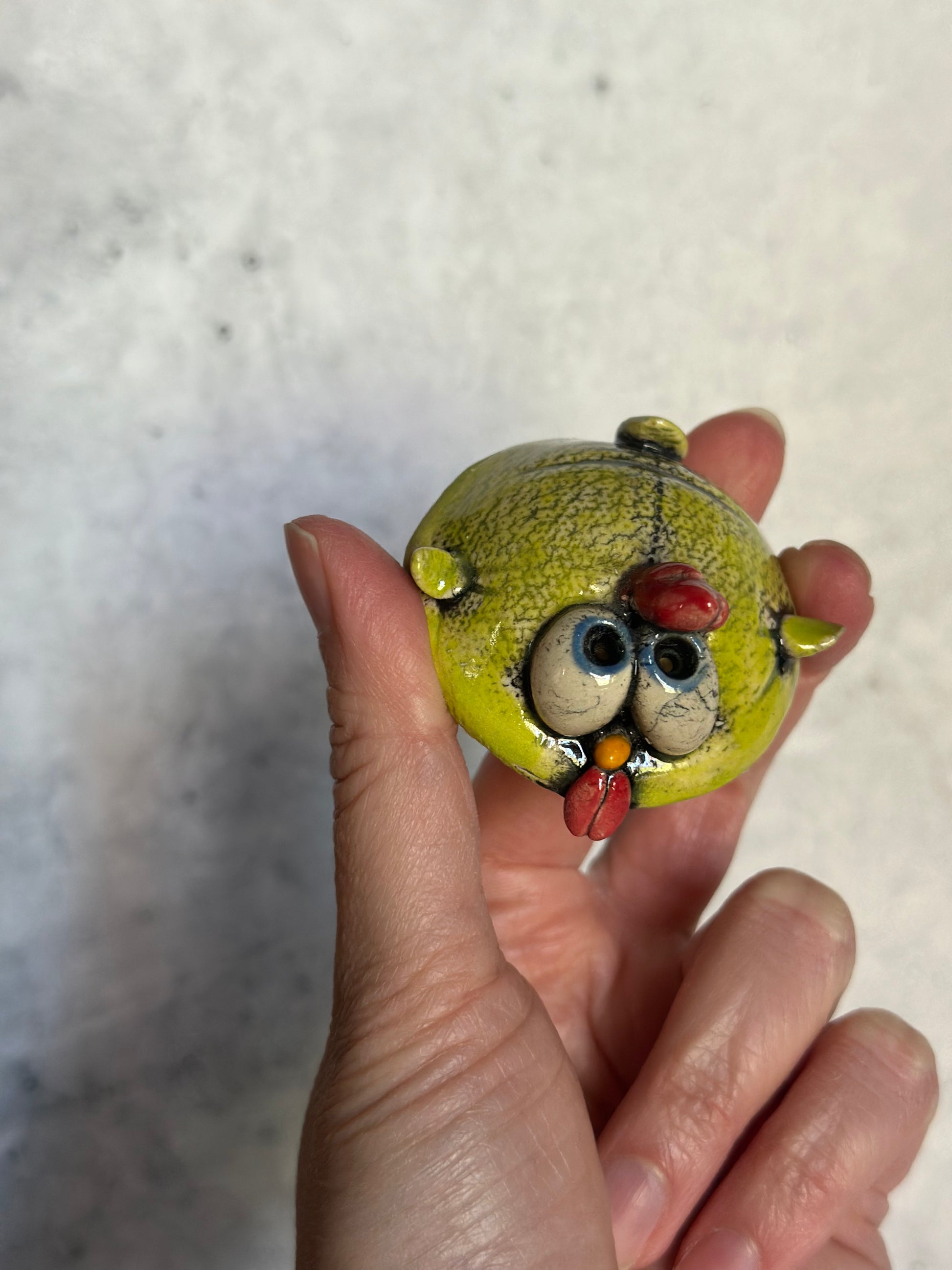 Hand holding a small chick against a neutral background
