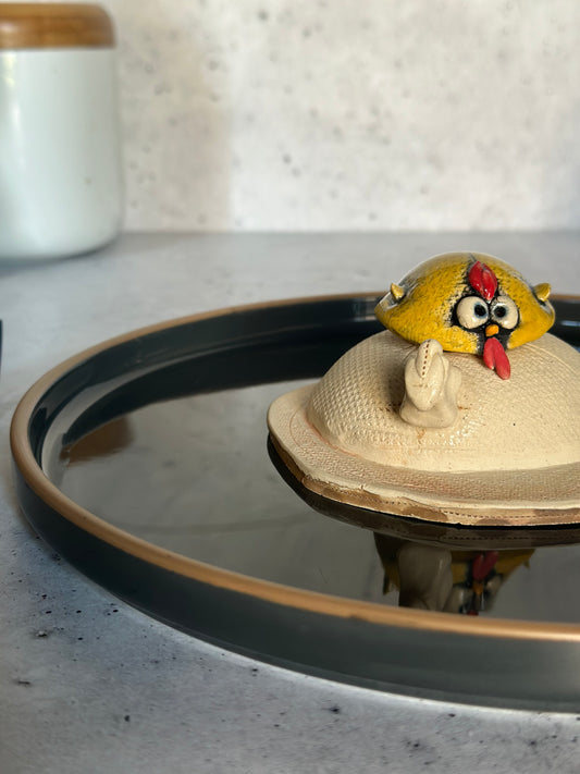 Ceramic egg with a yellow bird figurine on a stone surface