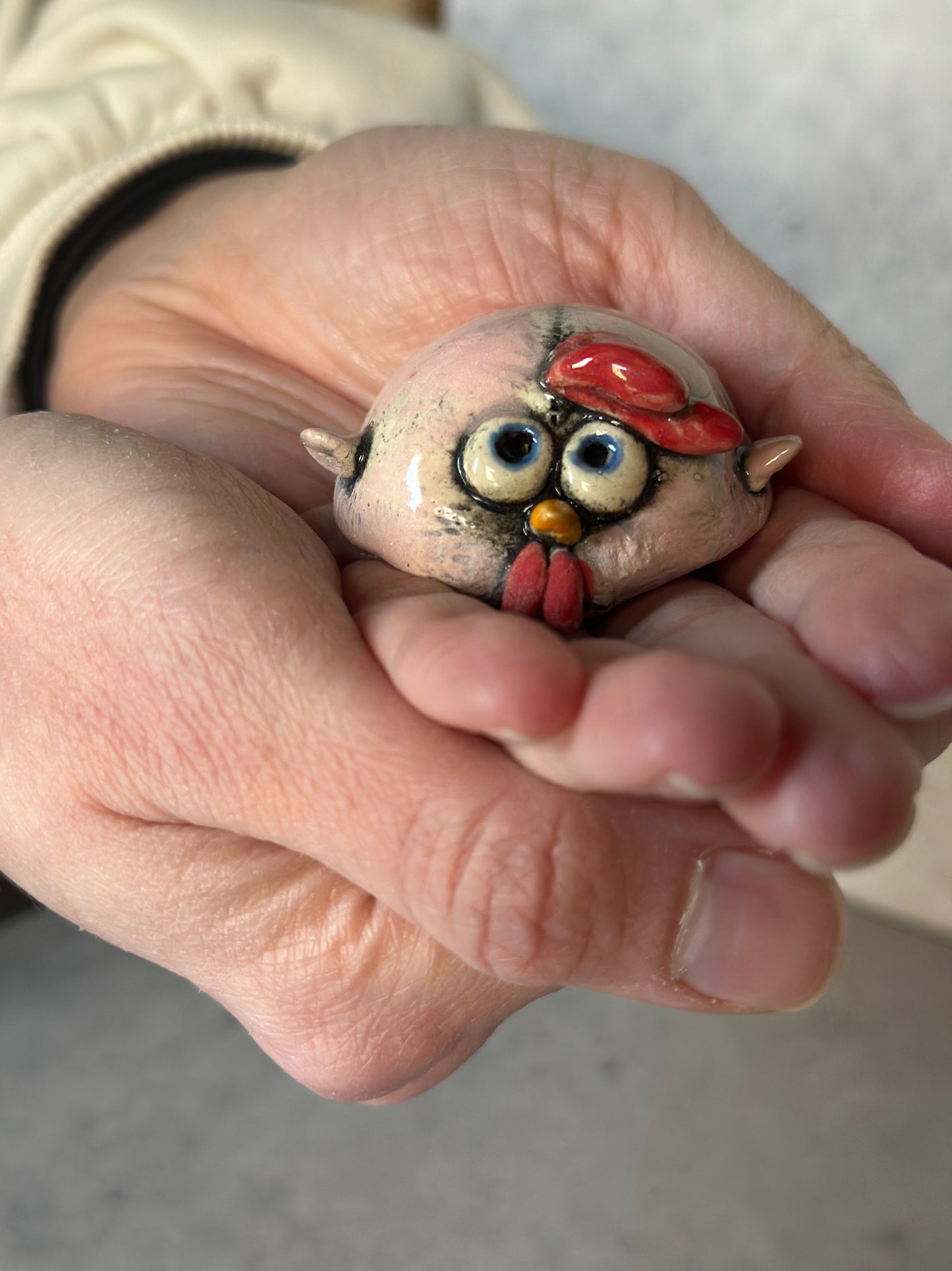 Hand holding a small ceramic chick figurine.