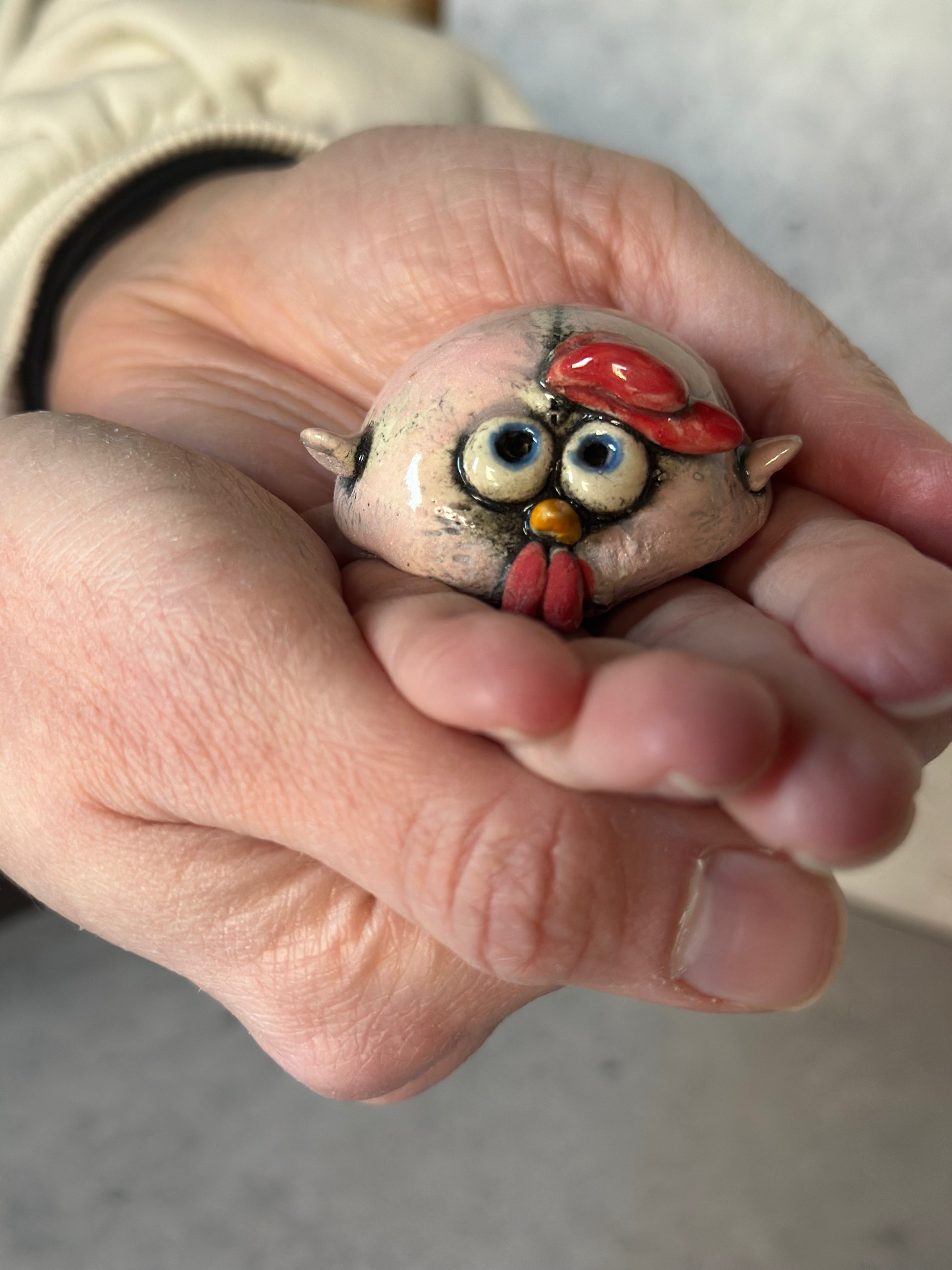 Hand holding a small ceramic chick figurine.