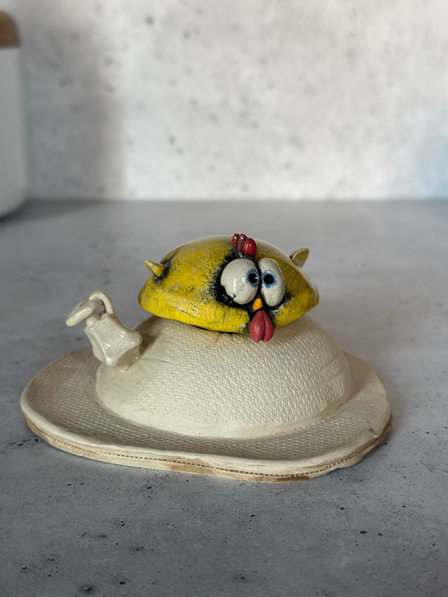 Decorative ceramic chicken on a gray surface.