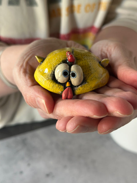 Hand holding a ceramic chicken with on a marble surface