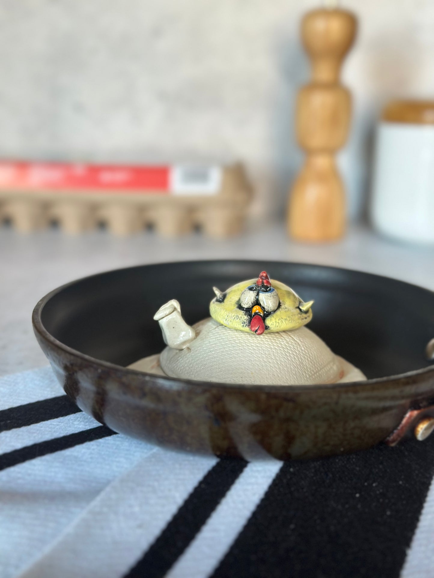Ceramic chick on a black pan with a blurred kitchen background