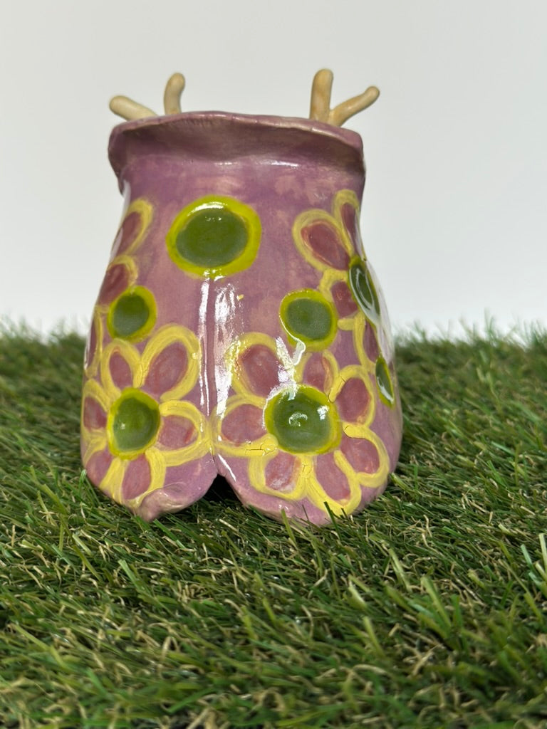 Ceramic tutrix with purple and yellow design on a grassy background
