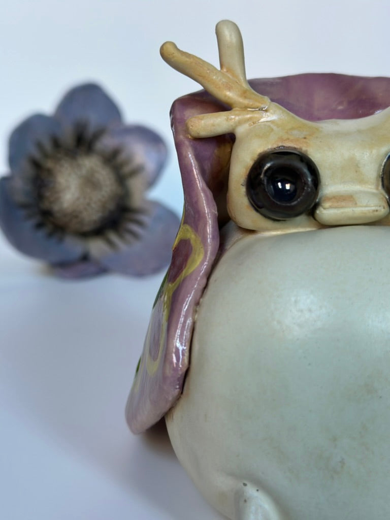 Ceramic tutrix figurine with a purple flower on a white background