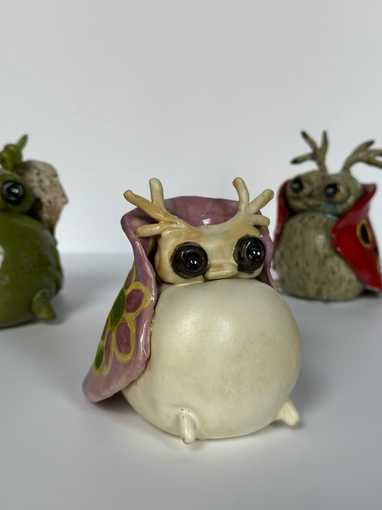 Three ceramic tutrix figurines with antlers on a white background