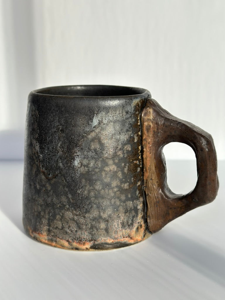 Black ceramic mug with a handle on a white background
