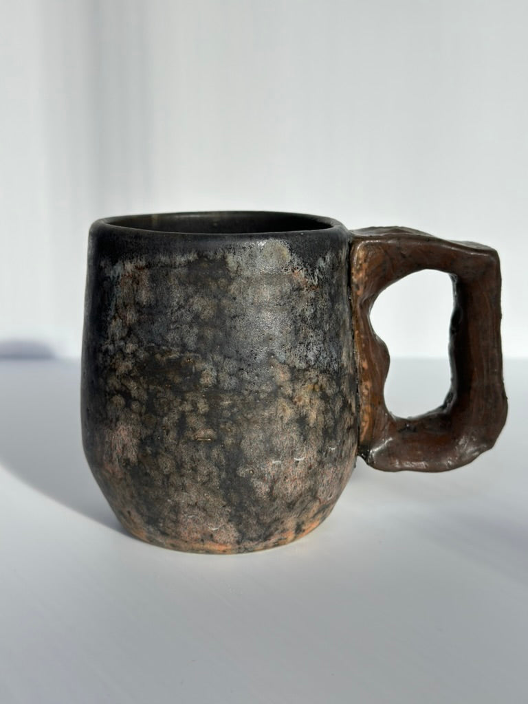 Ceramic mug with a unique handle design on a white background