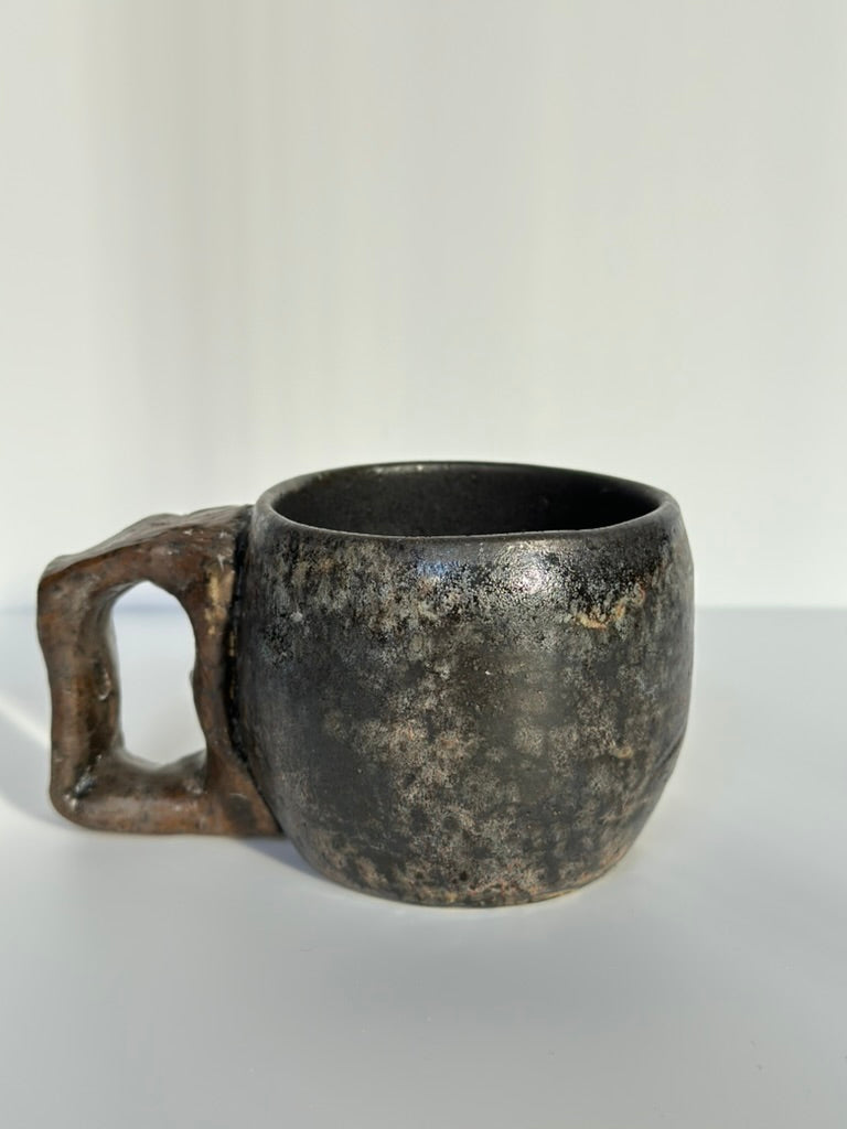 Black ceramic mug with a handle on a white background